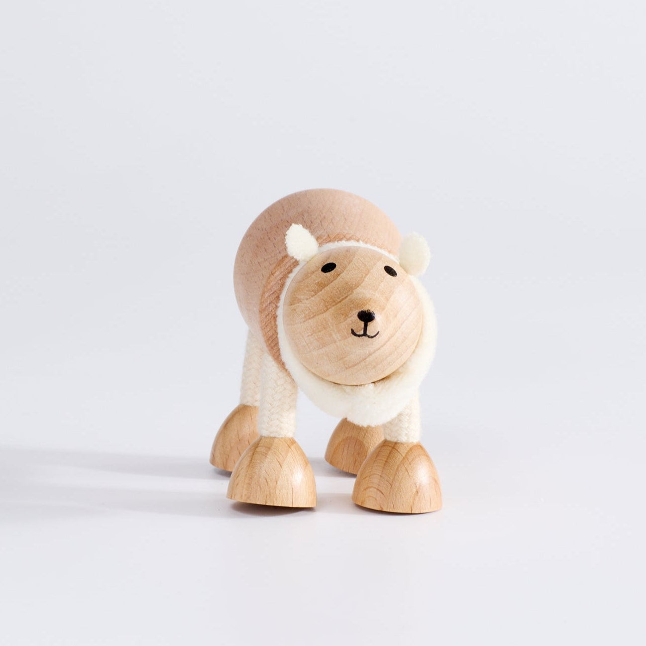 A wooden polar bear toy with a happy facial expression, standing upright on a white background.