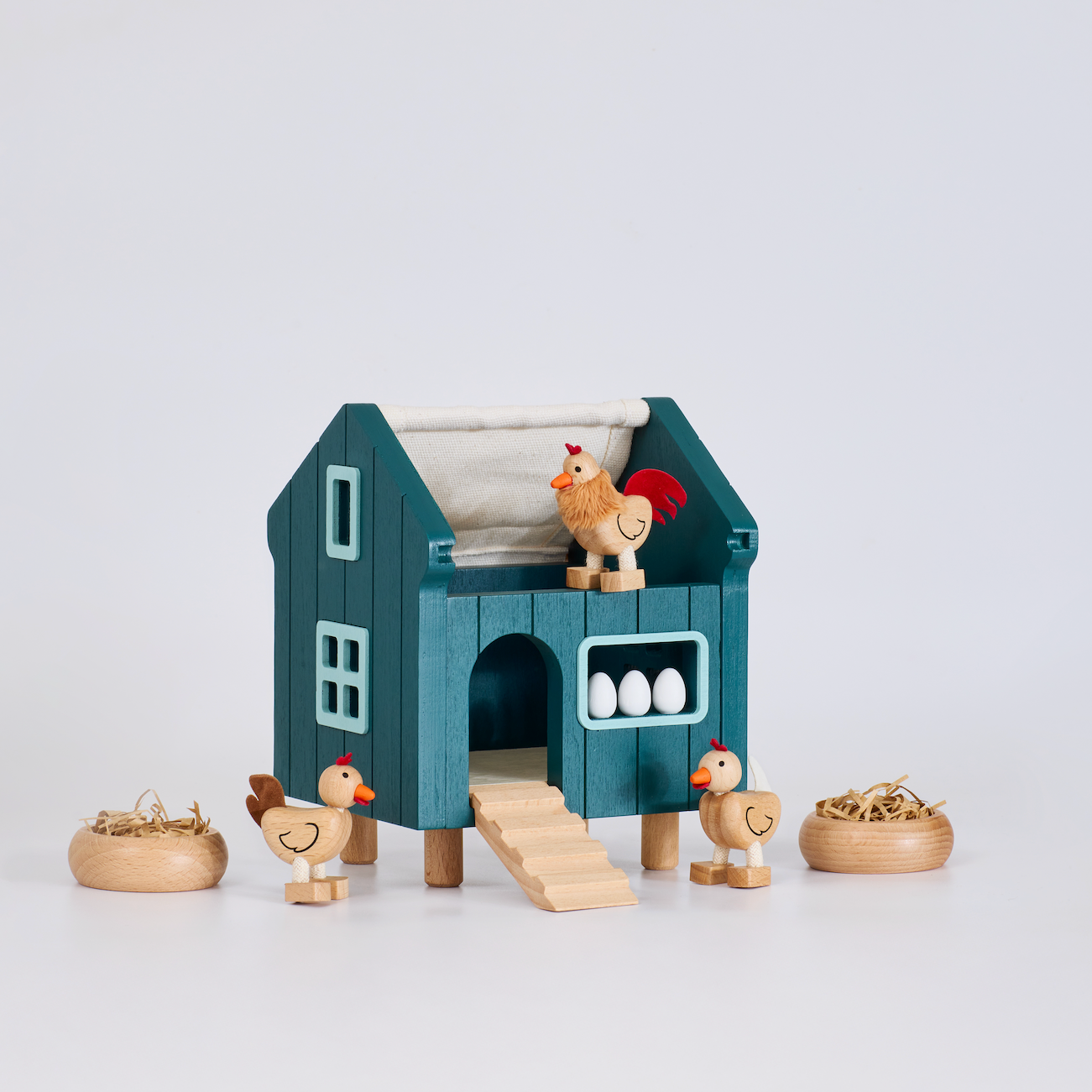 Toy chicken coop with chickens and eggs on a white background