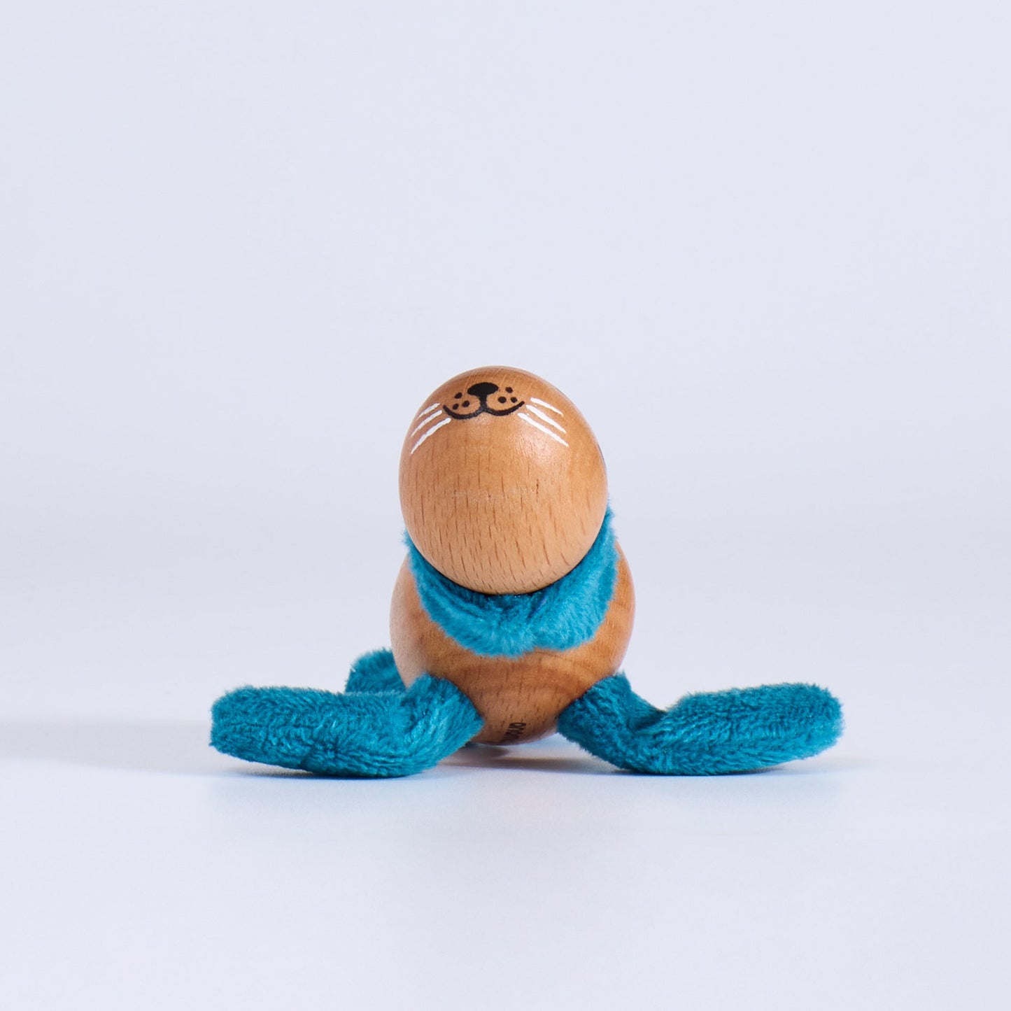 Wooden toy seal with a blue scarf on a white background