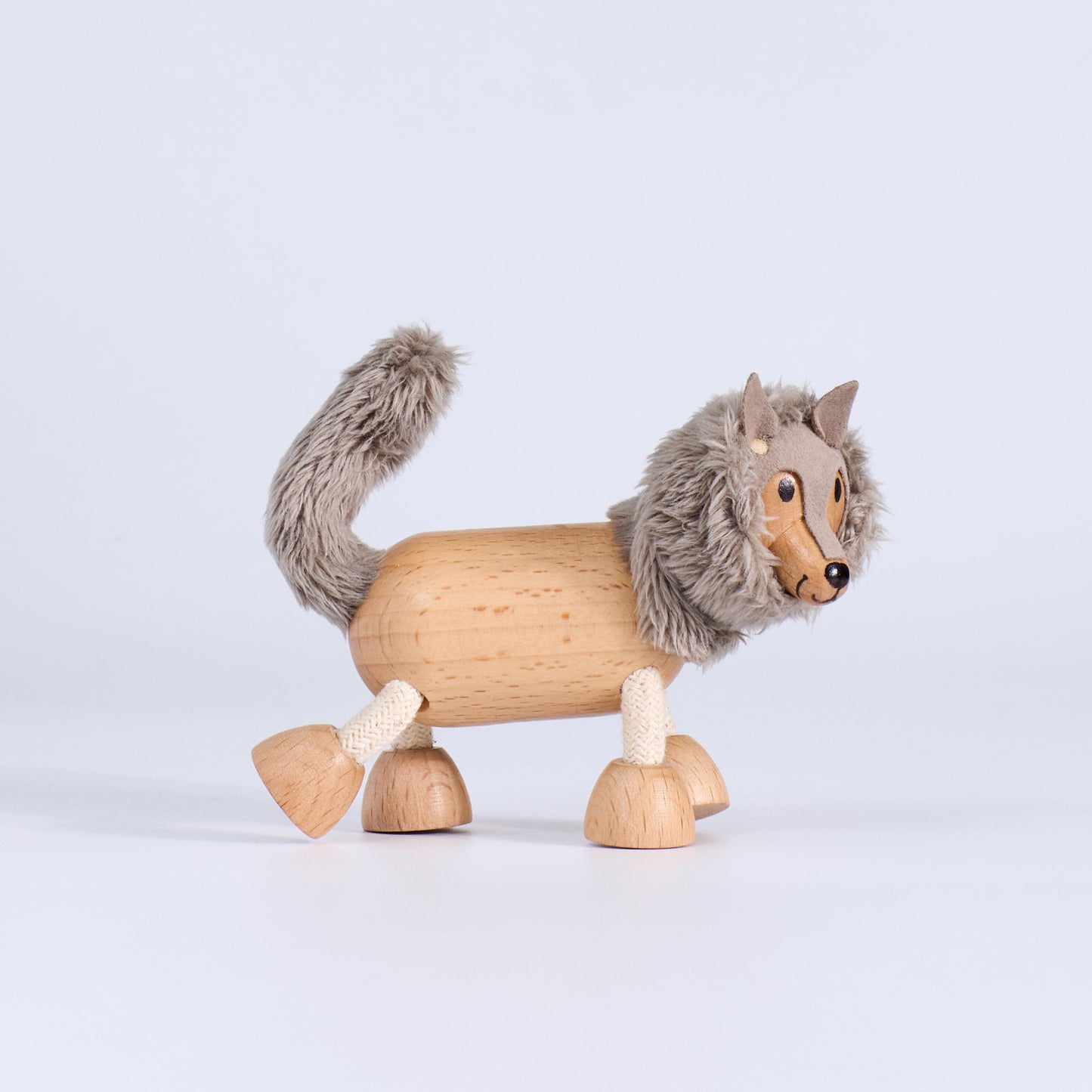 Wooden toy wolf with gray fur on a light gray background
