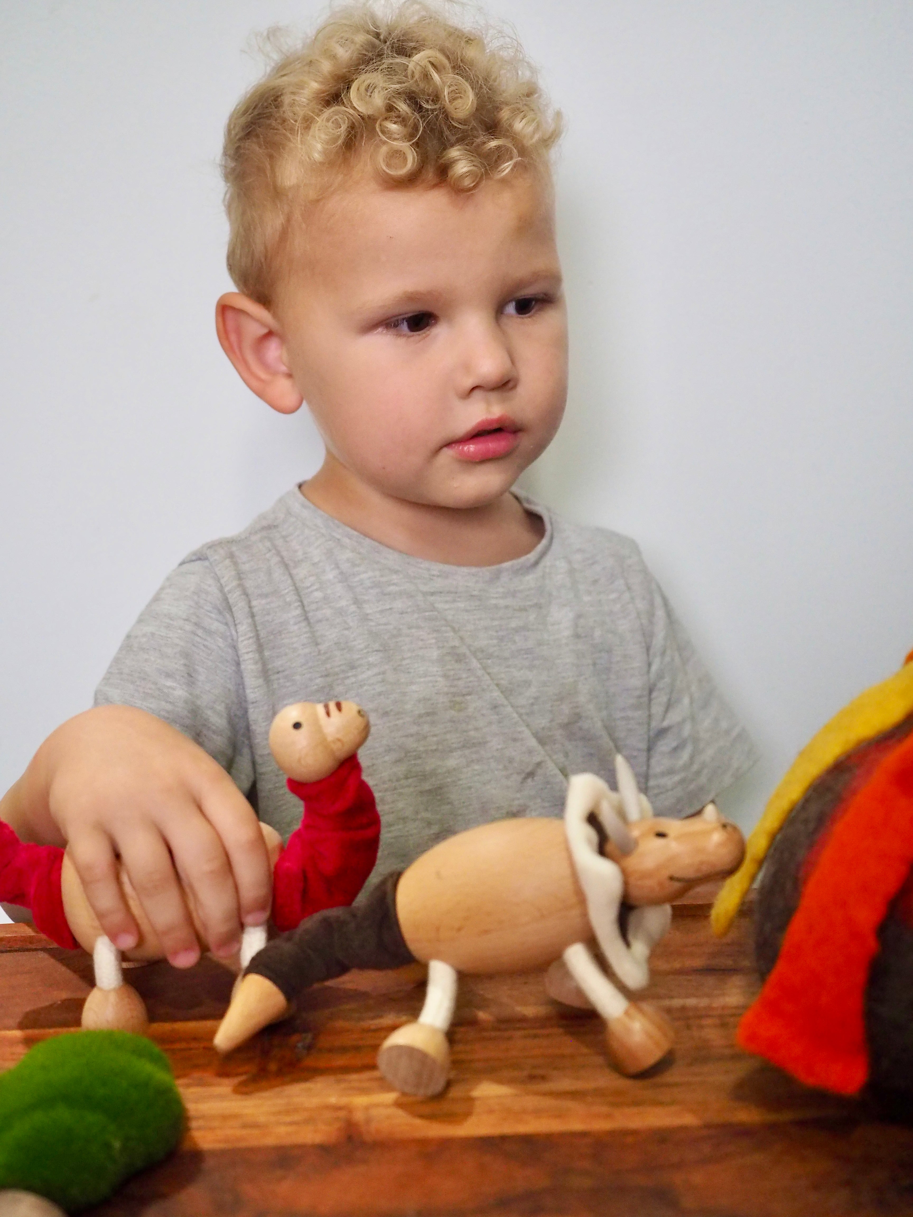 a small boy playing with wooden dinosaur toys on a table